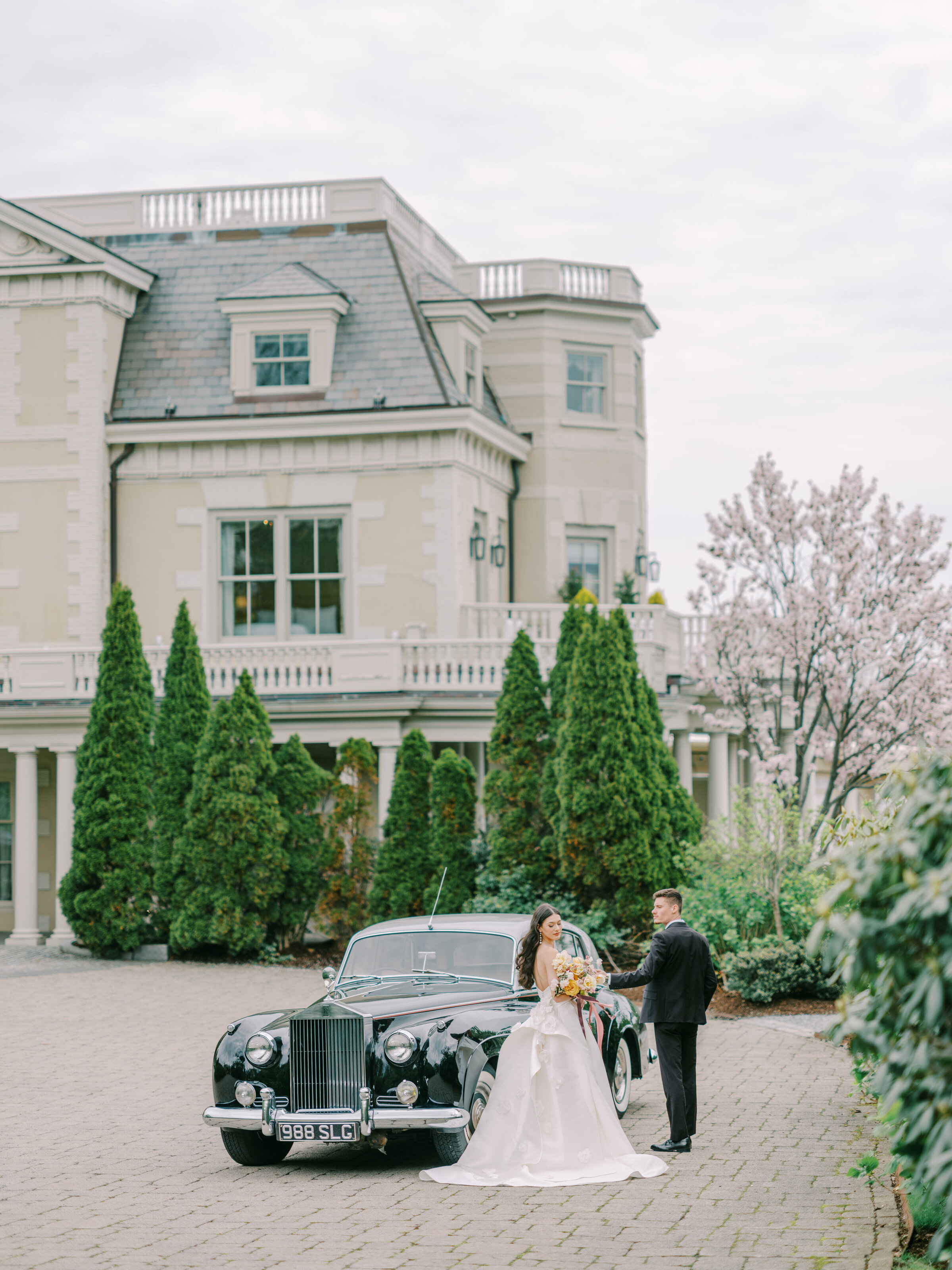 Newlyweds beside a vintage motorcar at a Newport mansion
